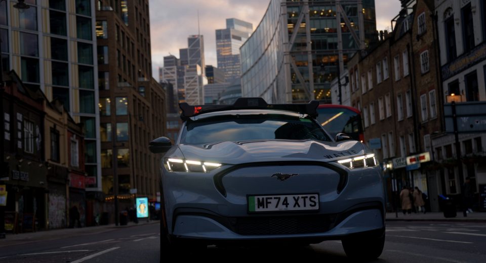 Self-driving vehicle driving through some streets in a busy city at sunset.