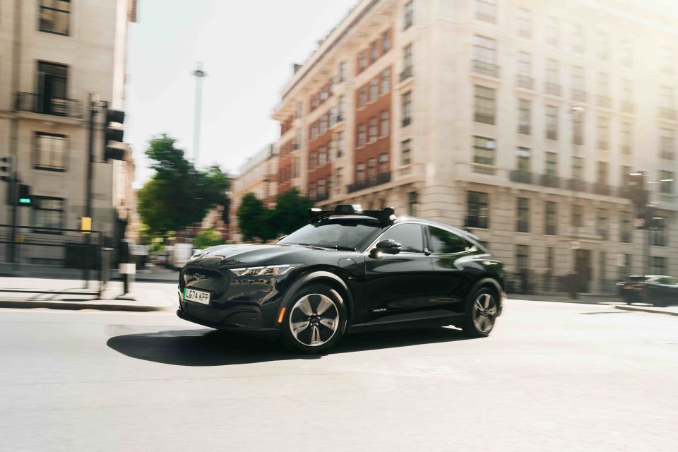 black car driving through a street on a sunny day
