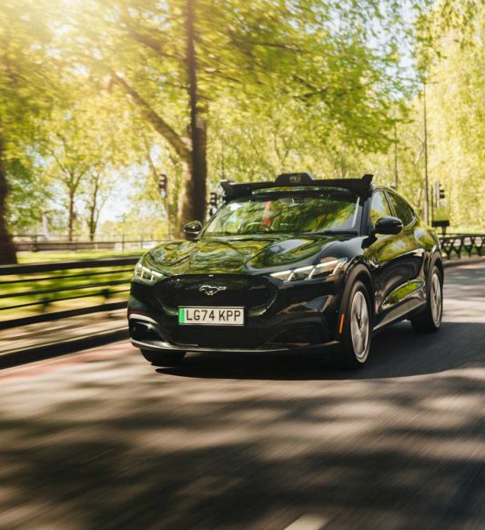 Wayve car navigating the streets around a park space with trees