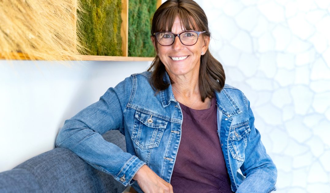 person sitting on a sofa in an office smiling at the camera